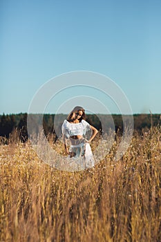 Beautiful young girl standing posing in the meadow on sunset