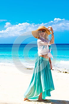 Beautiful young girl in a straw hat on a tropical beach