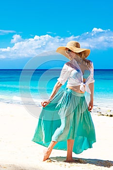 Beautiful young girl in a straw hat on a tropical beach