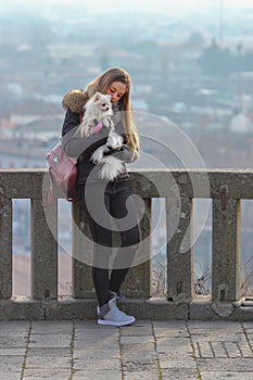 Beautiful young girl strolls with small white dog. German dwarf Spitz. Pomeranian