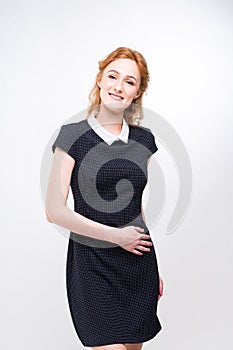 Beautiful young girl student, secretary or business lady with charming smile and red curly hair in black dress in white