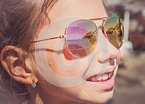 Beautiful young girl in sunglasses with beach reflection.