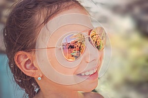 Beautiful young girl in sunglasses with beach reflection.