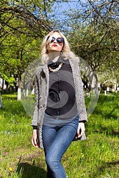 Beautiful young girl in sunglasses walking on a bright sunny summer day on city streets