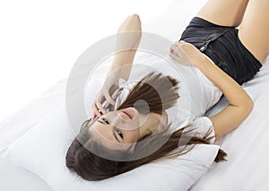 Beautiful young girl talking on mobilephone while lying on bed