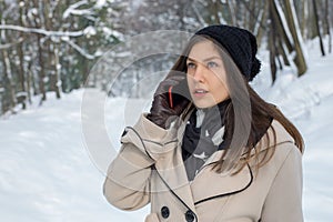 Beautiful young girl talking on the phone outside in a snowy for