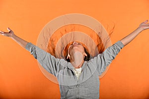 Beautiful and young girl throws up hair and holds hands in sides, concept of freedom and independence