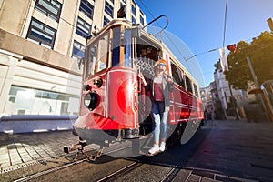 Beautiful young girl tourist in a hat poses in front of Taksim tram at popular Istiklal street in Beyoglu, Istanbul, Turkey