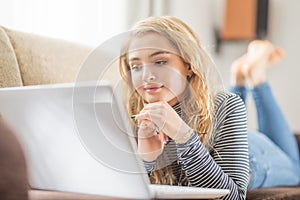 Beautiful young girl using laptop computer in living room