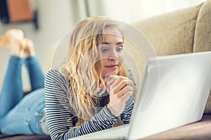 Beautiful young girl using laptop computer in living room