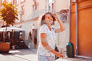 Beautiful young girl using smartphone and listening to the music walking on street. Woman dancing and singing