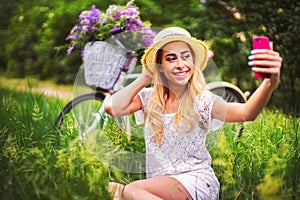 Beautiful young girl with vintage bicycle and flowers on city background in the sunlight outdoor.