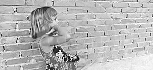 A beautiful young girl is walking down the street, a woman is against a brick wall, a black and white photo of a stylish