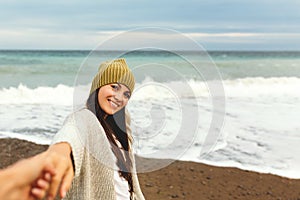 A beautiful young girl walks along the seashore, a storm, hair fly apart, a gray cardigan, a sports figure in sneakers