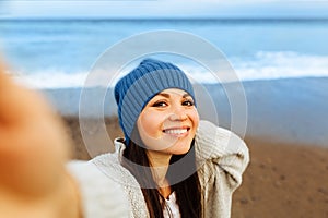 A beautiful young girl walks along the seashore, a storm, hair fly apart, a gray cardigan, a sports figure in sneakers