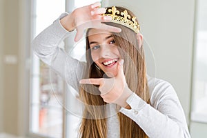 Beautiful young girl wearing a golden crown as a princess from fairytale smiling making frame with hands and fingers with happy