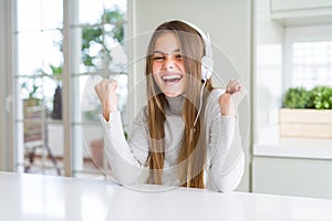 Beautiful young girl wearing headphones listening to music and dancing screaming proud and celebrating victory and success very