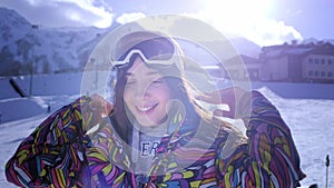 Beautiful young girl wearing ski goggles. Smiles and gets pleasure from the winter holidays. Ready to ski or snowboard