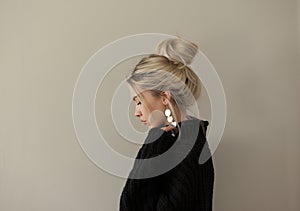 Beautiful young girl wearing warm black sweater and fashion jewellery over pastel background