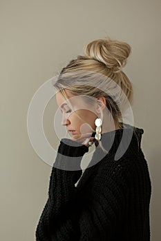 Beautiful young girl wearing warm black sweater and fashion jewellery over pastel background