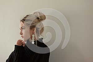 Beautiful young girl wearing warm black sweater and fashion jewellery over pastel background