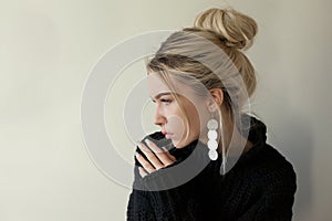 Beautiful young girl wearing warm black sweater and fashion jewellery over pastel background