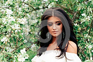 Beautiful young girl in white dress in spring blossoming apple orchards