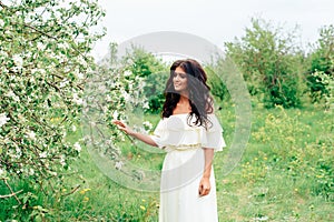 Beautiful young girl in white dress in spring blossoming apple orchards