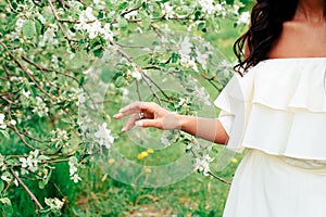 Beautiful young girl in white dress in spring blossoming apple orchards