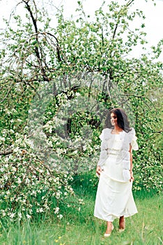 Beautiful young girl in white dress in spring blossoming apple orchards