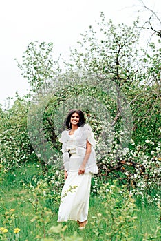 Beautiful young girl in white dress in spring blossoming apple orchards