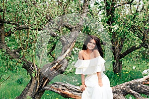 Beautiful young girl in white dress in spring blossoming apple orchards