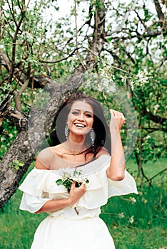 Beautiful young girl in white dress in spring blossoming apple orchards