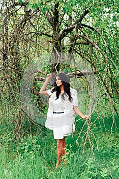 Beautiful young girl in white dress in spring blossoming apple orchards