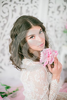 Beautiful young girl in a white lace dress with peony flowers