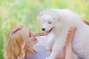 Beautiful young girl with a white puppy in her arms on a retro sofa in a summer garden