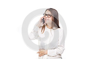 Beautiful young girl in a white shirt on white isolated background talking on a mobile phone. Smiles portrait to the waist