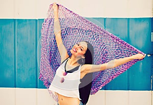 A beautiful young girl in a white t-shirt and blue jeans holds a large multi-colored handkerchief at arm`s length