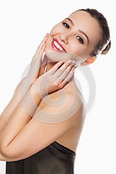 Beautiful young girl with white teeth, well maintained clean skin, bare shoulders, smile, hands, palms on cheeks, close-up