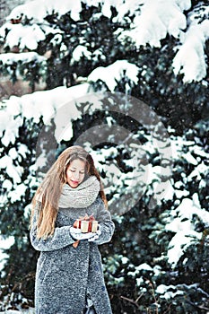 beautiful young girl in winter forest holding decoration