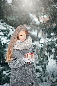 beautiful young girl in winter forest holding decoration