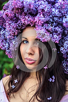 Beautiful young girl in a wreath of lilac.
