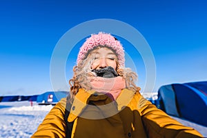 Beautiful young girl in a yellow down jacket and pink knitted cap with red hair in a frost in the background of the camp Barneo