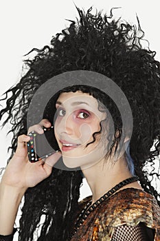 Beautiful young Goth woman with teased hair using mobile phone