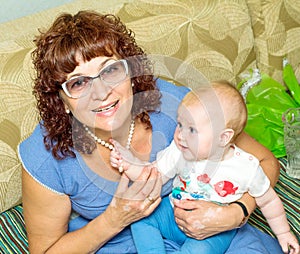 A beautiful young grandmother is holding her little nursing granddaughter