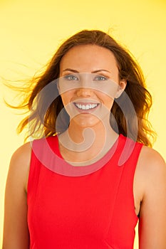 Beautiful young haapy woman in vibrant dre dress over yellow background photo