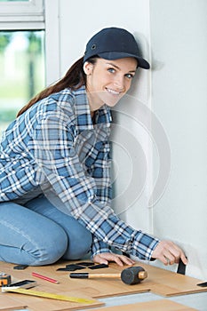 Beautiful young handywoman fitting floor boards