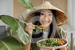 Beautiful young and happy asian woman eating healthy salad with fresh organic vegetables