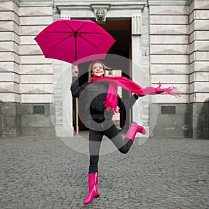 Beautiful young and happy blond woman with colorful umbrella on the street. The concept of positivity and optimism