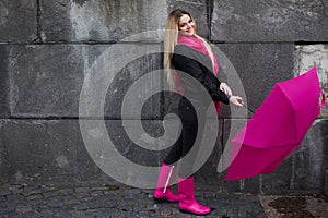 Beautiful young and happy blond woman with colorful umbrella on the street. The concept of positivity and optimism